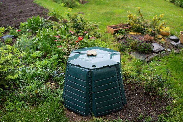 Outdoor composting bin for recycling kitchen and garden organic waste in a lovely lush garden